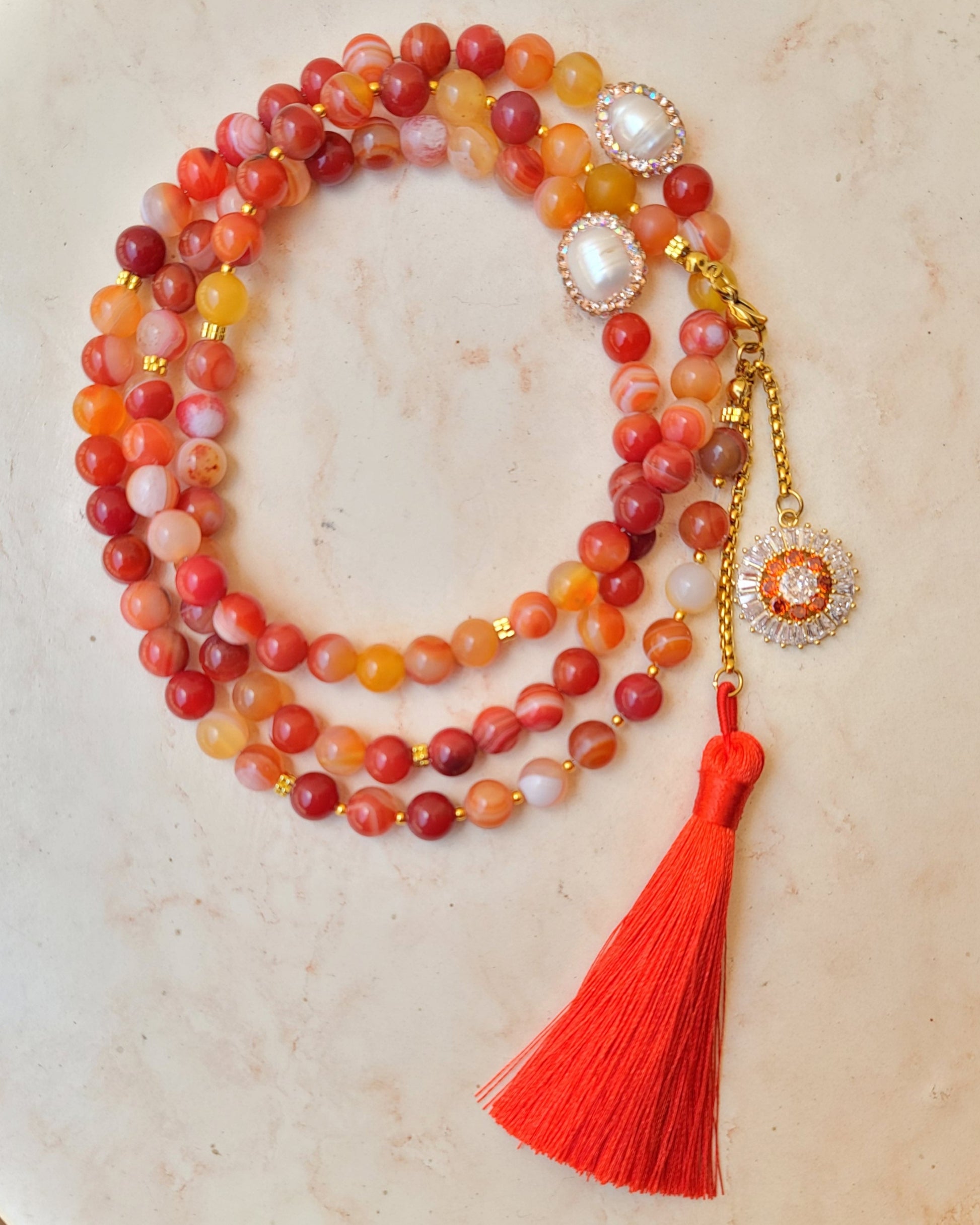 Beaded necklace with a red tassel on a beige surface